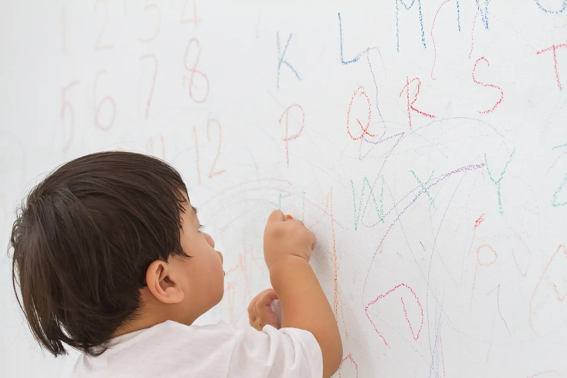 子供がホワイトボードに英字を書いている様子