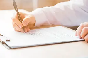 申込書類を記入する手のアップ